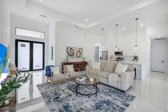 living room with visible vents, french doors, a tray ceiling, and a towering ceiling