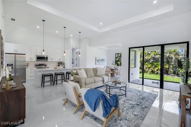 living area featuring a tray ceiling, recessed lighting, visible vents, and a towering ceiling