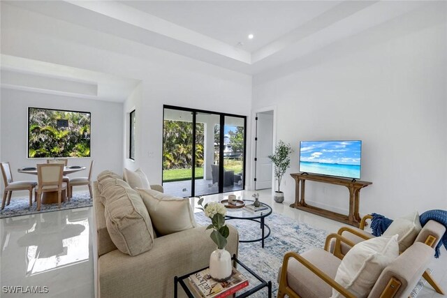 living room featuring recessed lighting, a raised ceiling, and a high ceiling