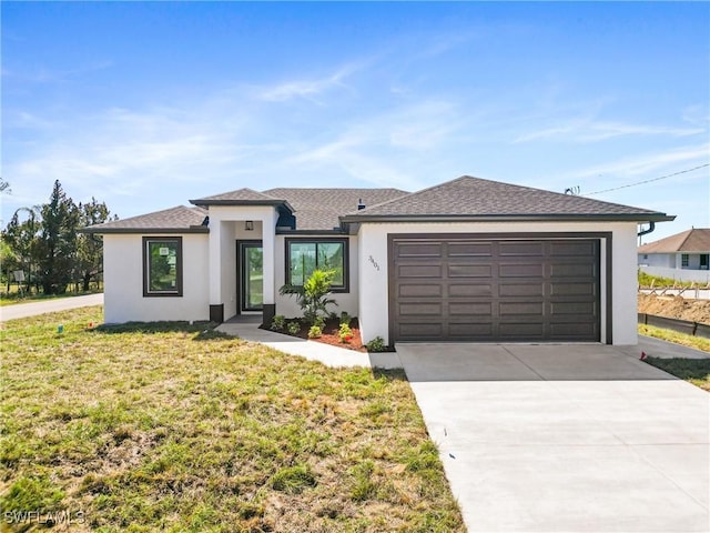 prairie-style home with concrete driveway, stucco siding, roof with shingles, an attached garage, and a front yard