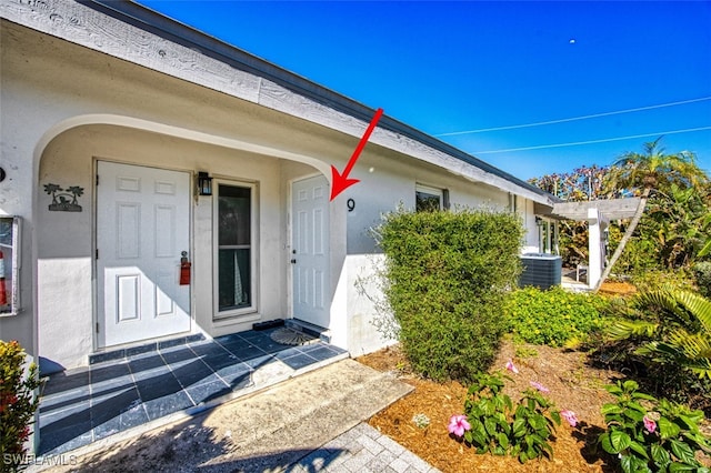 property entrance featuring stucco siding and central air condition unit