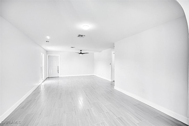 spare room featuring visible vents, a ceiling fan, light wood-type flooring, and baseboards