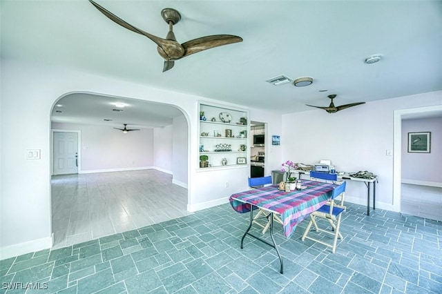 dining area featuring arched walkways, visible vents, baseboards, and a ceiling fan