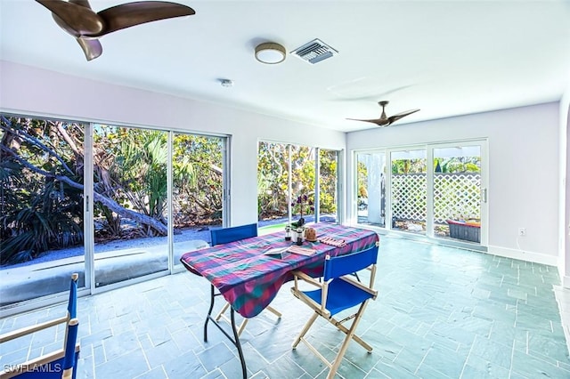 dining area with a ceiling fan, baseboards, visible vents, and stone finish flooring