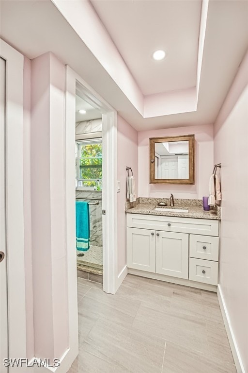 full bathroom with recessed lighting, baseboards, a raised ceiling, and vanity