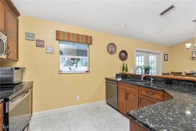 kitchen featuring dark stone countertops, visible vents, stainless steel appliances, and a sink