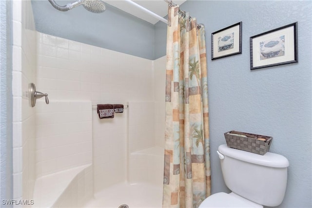 bathroom with curtained shower, a textured wall, and toilet