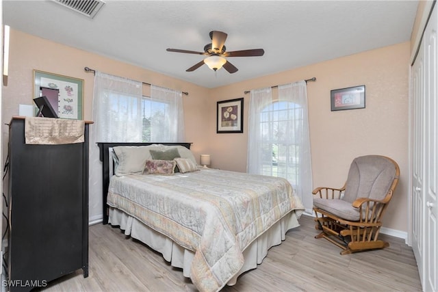 bedroom featuring baseboards, visible vents, ceiling fan, light wood-style floors, and a closet