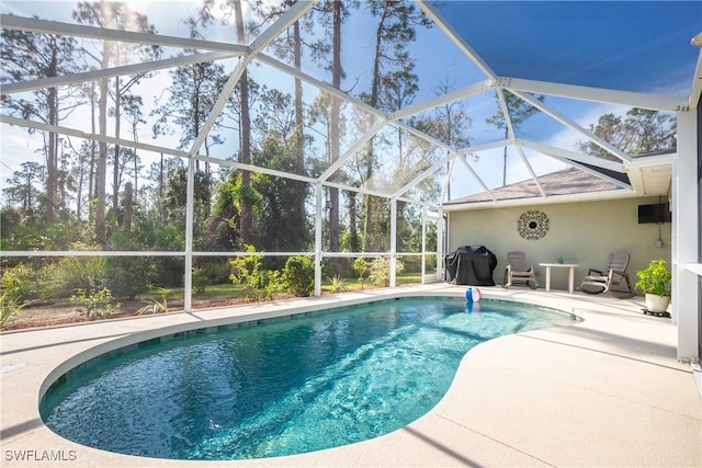 outdoor pool with glass enclosure, area for grilling, and a patio