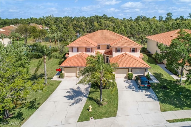 mediterranean / spanish house featuring stucco siding, concrete driveway, a front yard, an attached garage, and a tiled roof