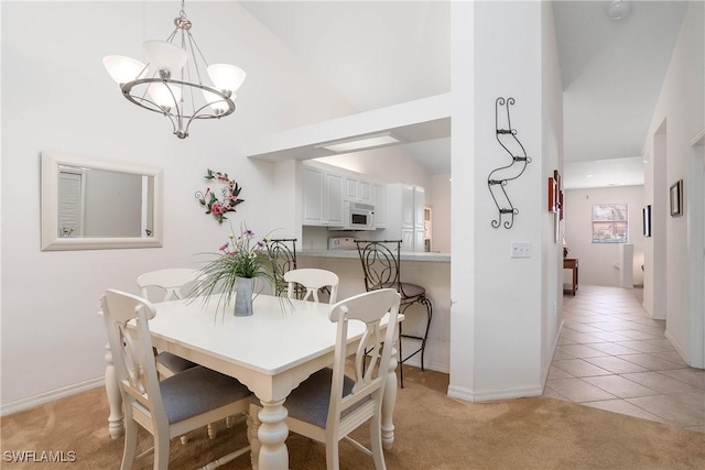 dining room with a notable chandelier, light colored carpet, baseboards, and light tile patterned floors