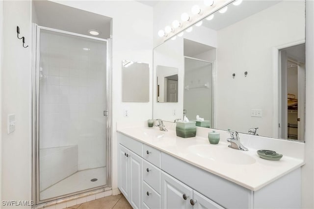 full bathroom with tile patterned flooring, double vanity, a stall shower, and a sink