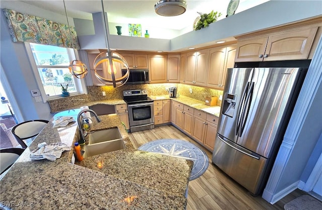 kitchen featuring appliances with stainless steel finishes, light brown cabinets, a sink, and decorative backsplash