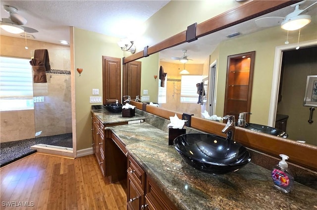 bathroom with a ceiling fan, vanity, a textured ceiling, wood finished floors, and walk in shower