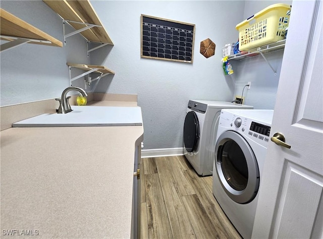 washroom featuring laundry area, washing machine and dryer, baseboards, and wood finished floors