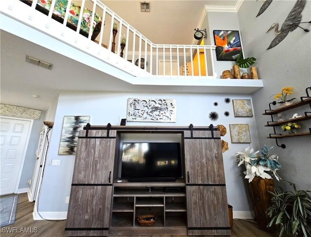 interior space featuring a barn door, wood finished floors, visible vents, and baseboards