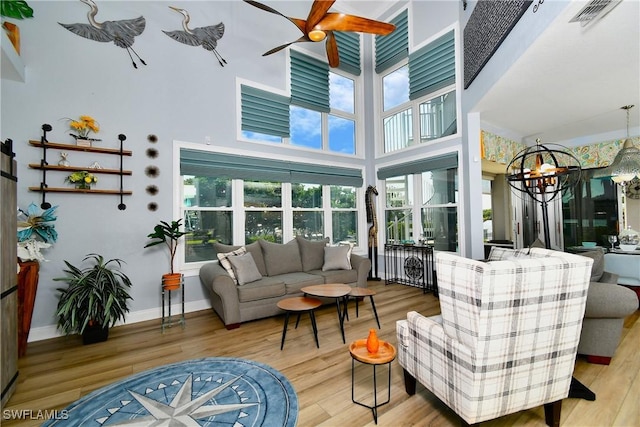 sunroom featuring ceiling fan with notable chandelier and visible vents