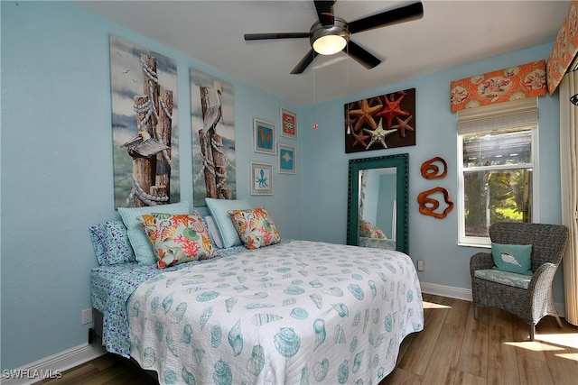 bedroom featuring ceiling fan, baseboards, and wood finished floors