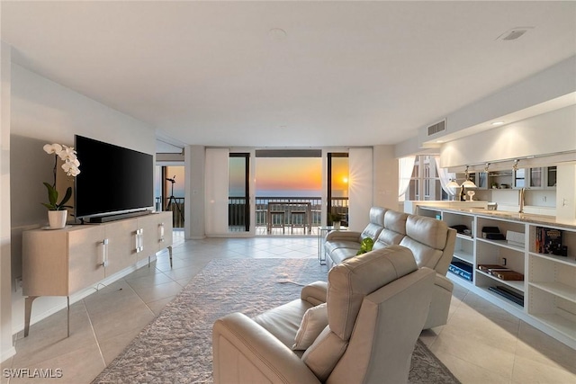 living room featuring light tile patterned flooring, visible vents, and expansive windows