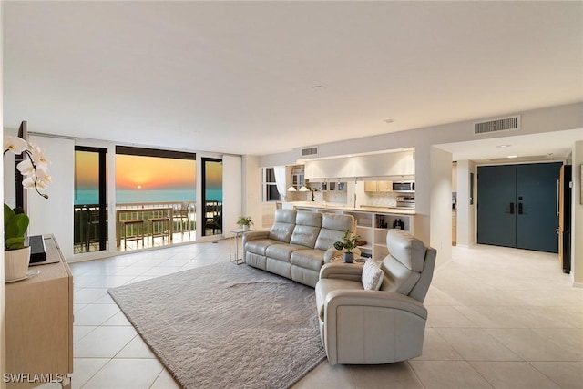 living area with light tile patterned floors, visible vents, floor to ceiling windows, and a water view