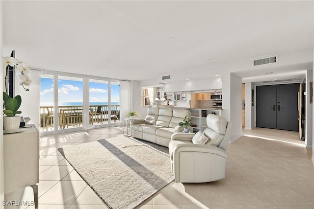 living room with light tile patterned floors, expansive windows, baseboards, and visible vents