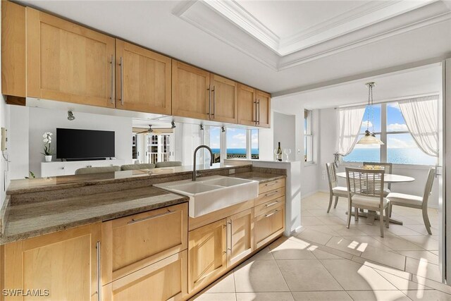 kitchen featuring light tile patterned floors, a tray ceiling, ornamental molding, a sink, and pendant lighting