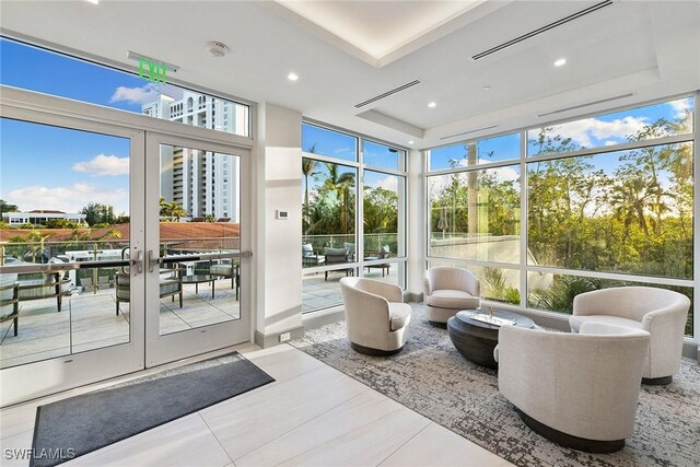 sunroom featuring french doors, plenty of natural light, and a raised ceiling