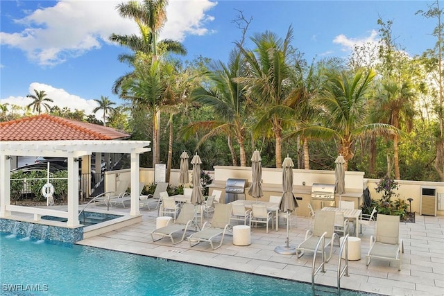 pool featuring fence, a patio area, a grill, exterior kitchen, and a hot tub