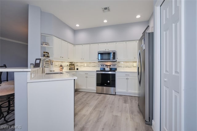 kitchen featuring open shelves, visible vents, appliances with stainless steel finishes, a sink, and a peninsula