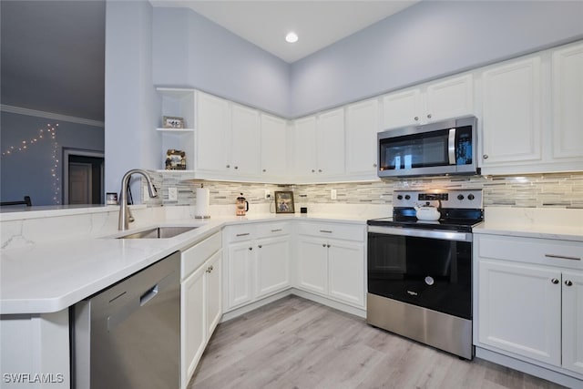 kitchen featuring stainless steel appliances, white cabinetry, a sink, and open shelves