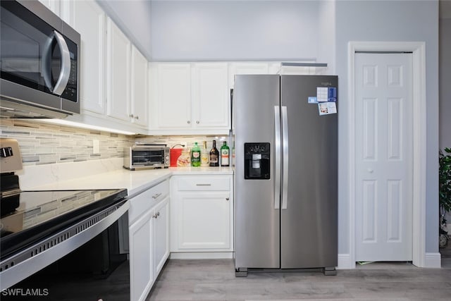 kitchen featuring stainless steel appliances, light wood-style floors, white cabinets, and decorative backsplash