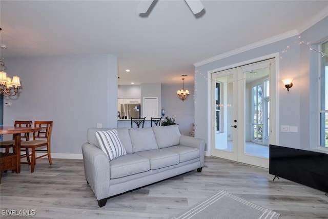 living room with crown molding, light wood finished floors, recessed lighting, baseboards, and ceiling fan with notable chandelier