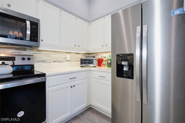 kitchen featuring stainless steel appliances, light wood-style floors, white cabinets, and decorative backsplash