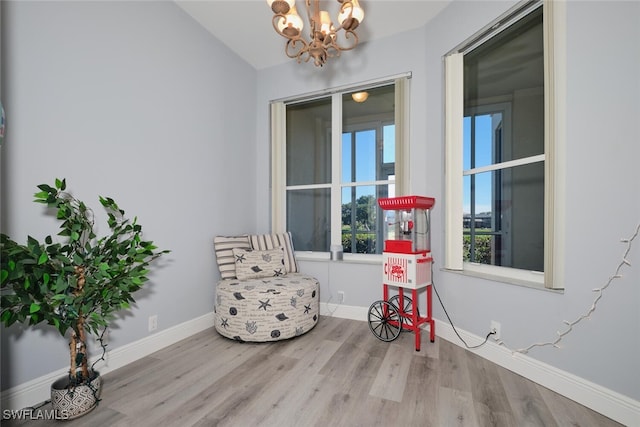 living area featuring a notable chandelier, baseboards, and wood finished floors