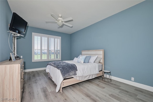 bedroom with light wood-style flooring, baseboards, and a ceiling fan