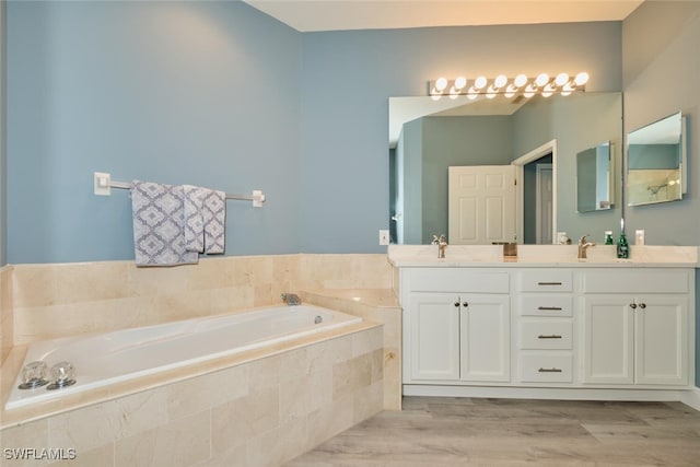 full bath with a sink, double vanity, wood finished floors, and a garden tub