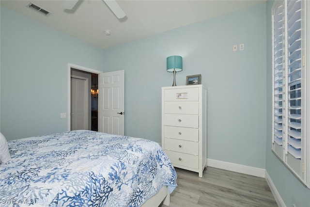 bedroom with light wood-style floors, visible vents, baseboards, and a ceiling fan