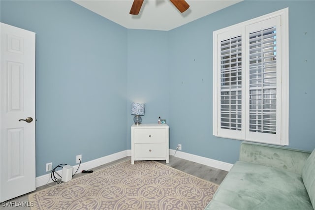 interior space with a ceiling fan, baseboards, and wood finished floors