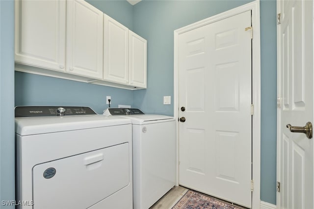 clothes washing area with light wood-type flooring, cabinet space, and washing machine and clothes dryer