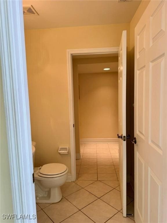 bathroom with tile patterned flooring, baseboards, visible vents, and toilet