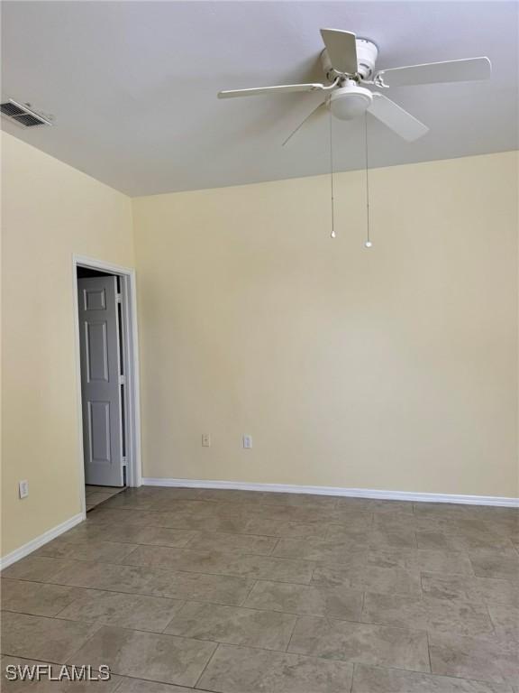 empty room featuring visible vents, ceiling fan, and baseboards