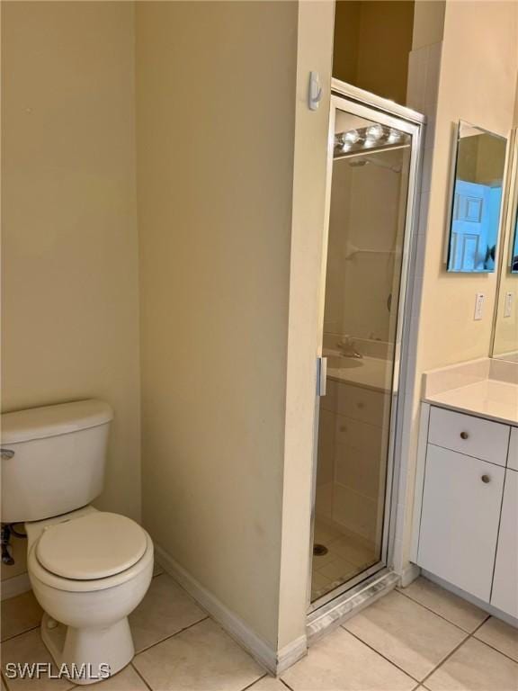 full bathroom featuring toilet, a shower stall, vanity, baseboards, and tile patterned floors