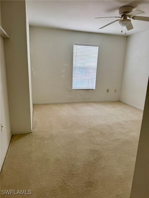 spare room with carpet floors, a ceiling fan, and baseboards