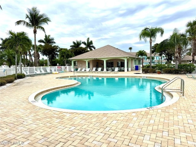 community pool with a patio area and fence