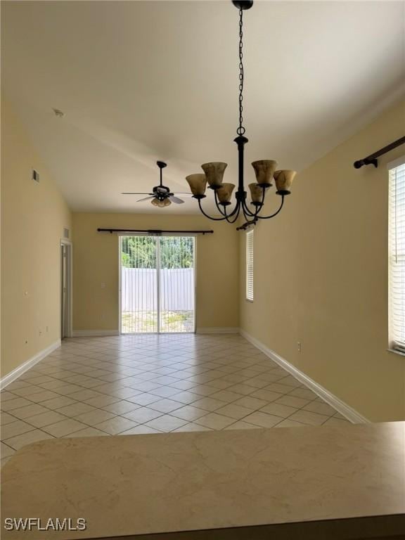 empty room featuring light tile patterned floors, lofted ceiling, ceiling fan with notable chandelier, visible vents, and baseboards