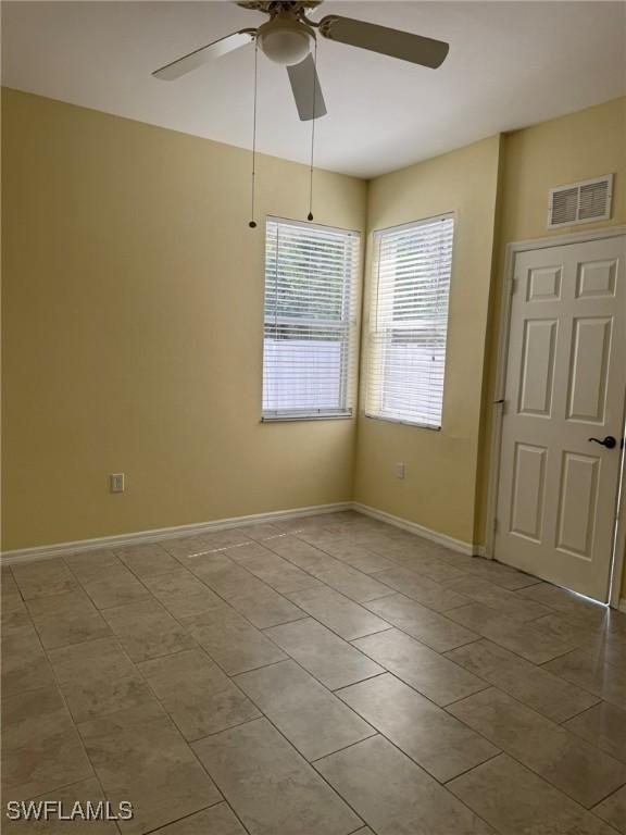 unfurnished room with a ceiling fan, tile patterned flooring, visible vents, and baseboards