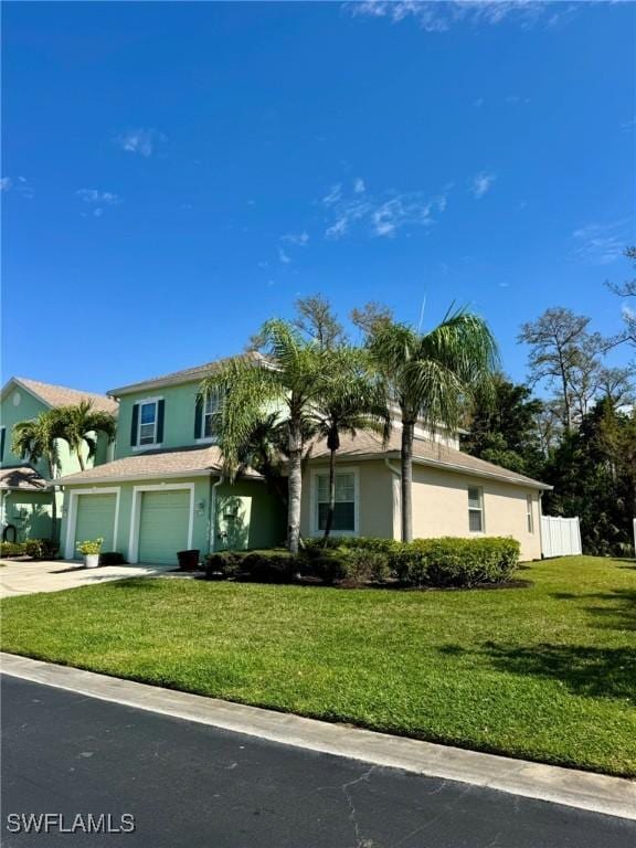 view of front facade featuring a front lawn, driveway, an attached garage, and stucco siding