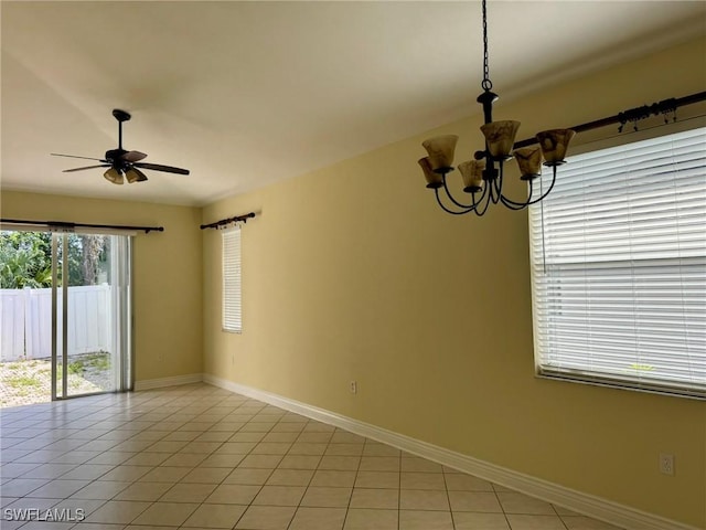 unfurnished room featuring ceiling fan with notable chandelier, baseboards, and light tile patterned flooring