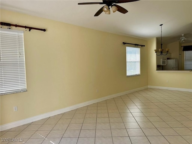 unfurnished room featuring light tile patterned floors, baseboards, and ceiling fan with notable chandelier