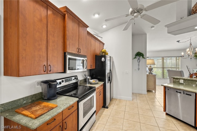 kitchen with brown cabinetry, ceiling fan with notable chandelier, stainless steel appliances, and light tile patterned flooring